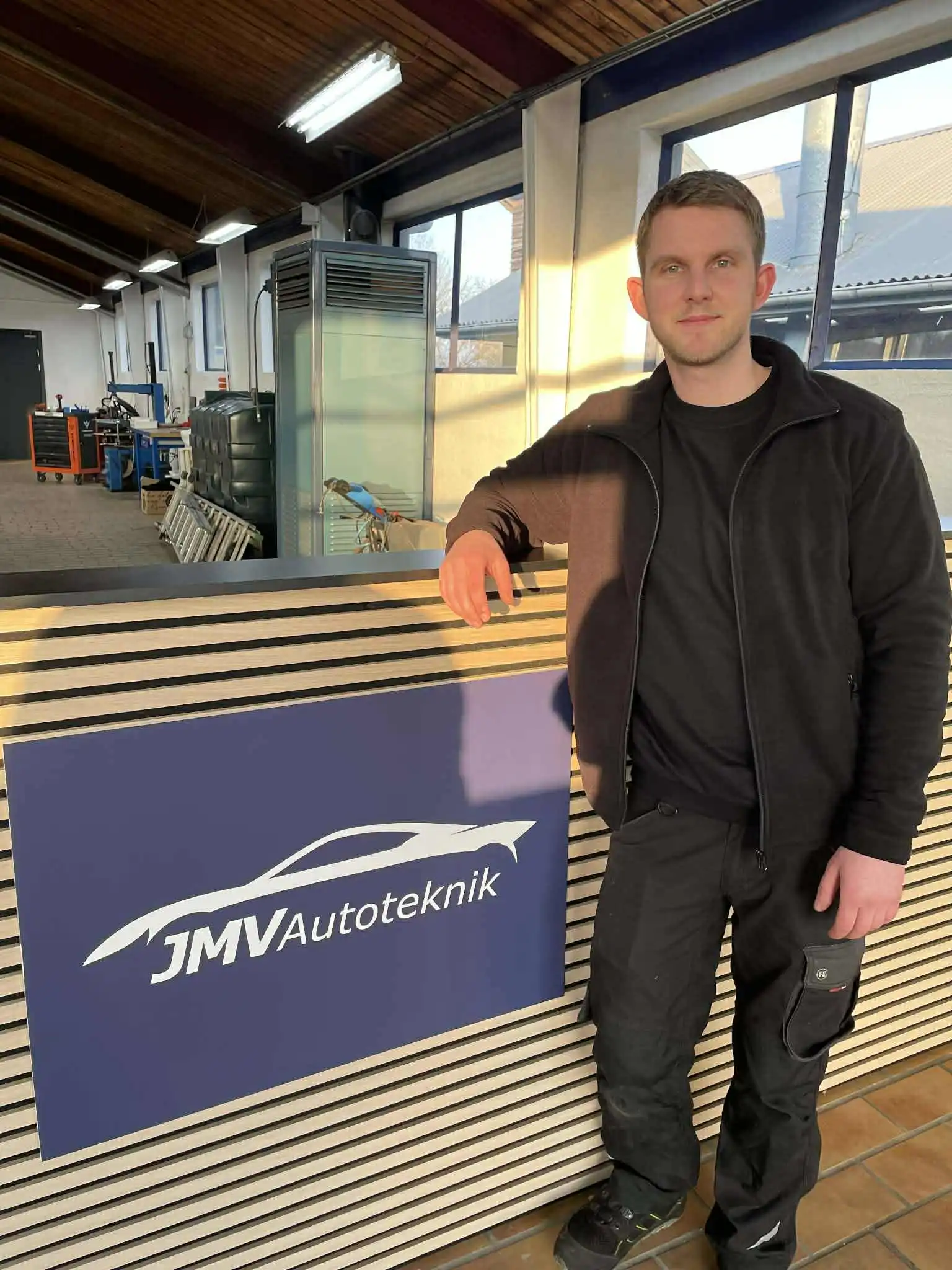 Ejer af værkstedet står med arme over kors